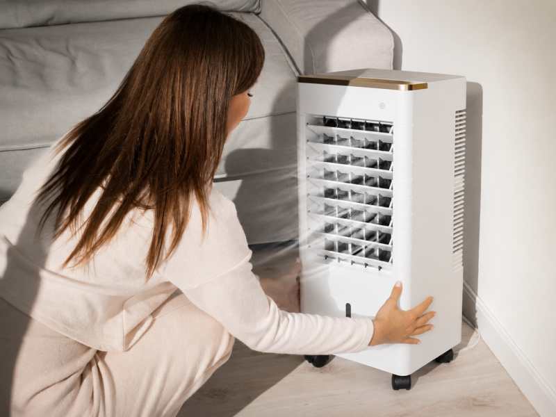 Femme installant un climatiseur mobile dans un salon lumineux pour profiter d’un air frais à la maison