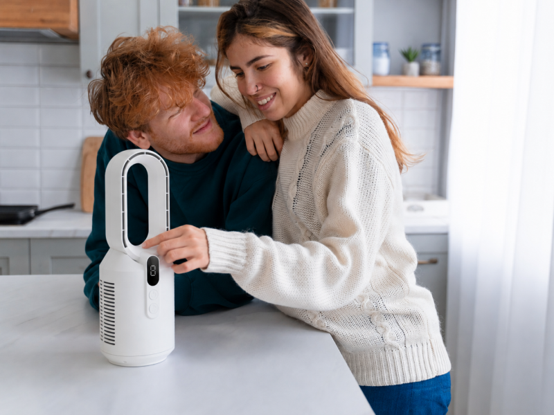 Couple utilisant un mini ventilateur sans pales dans une cuisine moderne pour profiter d’un air frais à la maison